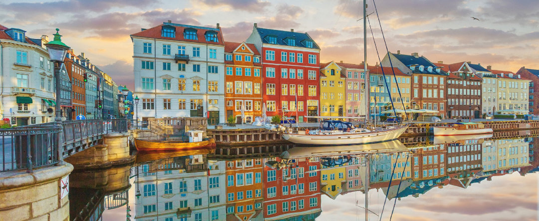 Barco turístico recorriendo uno de los canales de Copenhague bajo la puesta de sol.